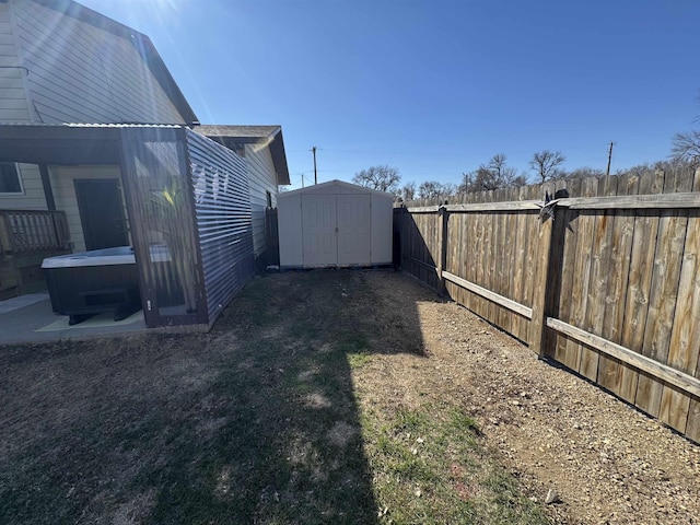 view of yard with an outdoor structure, a fenced backyard, a hot tub, and a shed