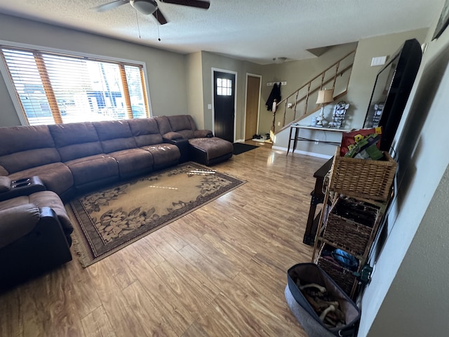 living area featuring stairs, a ceiling fan, a textured ceiling, and wood finished floors
