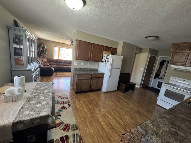 kitchen with a textured ceiling, dark wood-style flooring, open floor plan, and white appliances