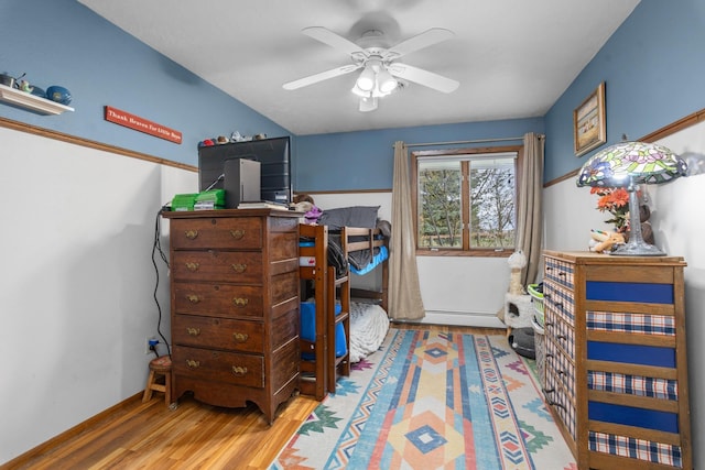 9500 135th Ave, Sawyer, ND 58781 - bedroom featuring a baseboard heating unit, ceiling fan, and wood finished floors