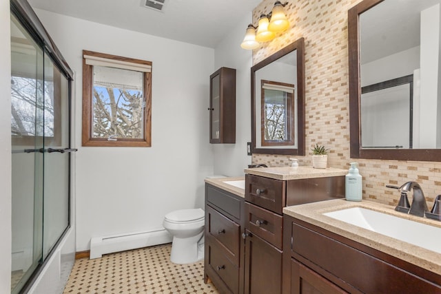 9500 135th Ave, Sawyer, ND 58781 - full bathroom with a sink, baseboard heating, toilet, double vanity, and backsplash
