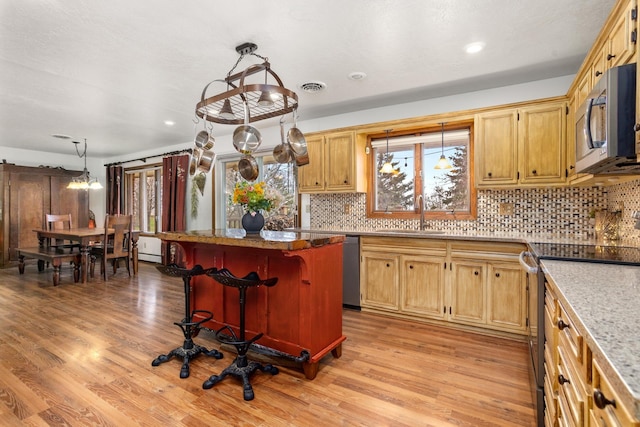 9500 135th Ave, Sawyer, ND 58781 - kitchen with a kitchen island, backsplash, a sink, light wood-style floors, and stainless steel appliances
