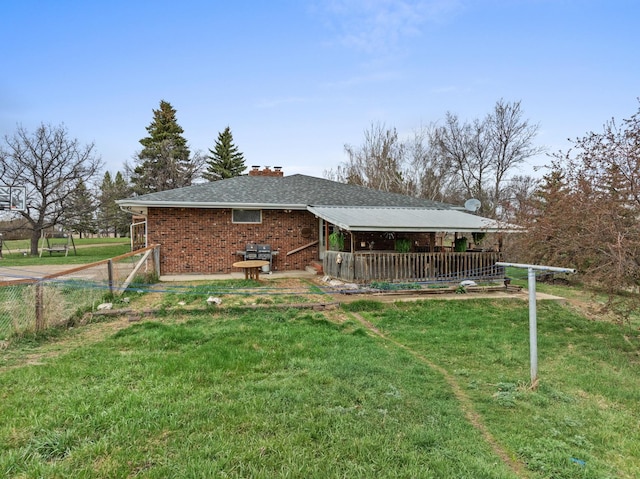 9500 135th Ave, Sawyer, ND 58781 - rear view of property featuring a chimney, a lawn, a deck, brick siding, and fence