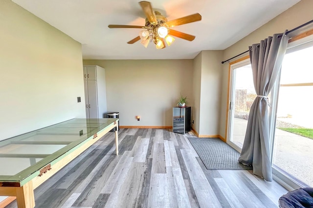 interior space with baseboards, a ceiling fan, and light wood-style flooring