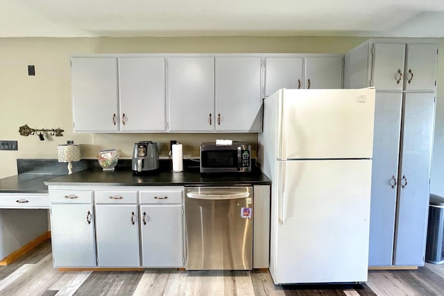 kitchen with light wood-style floors, appliances with stainless steel finishes, white cabinets, and dark countertops