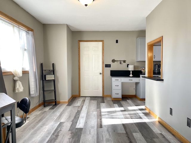 home office with baseboards and light wood-style flooring