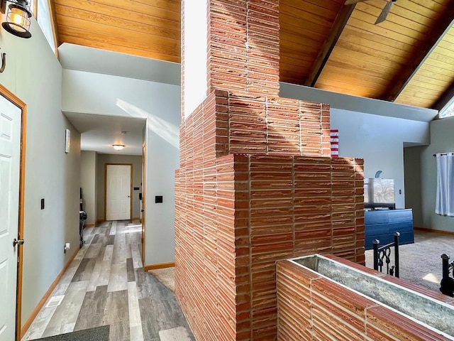 corridor featuring baseboards, lofted ceiling with beams, wooden ceiling, and wood finished floors
