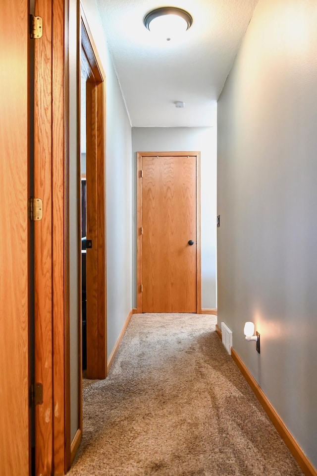 hall featuring carpet floors, baseboards, and visible vents