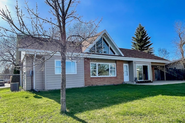 rear view of property featuring a lawn, a patio area, fence, and brick siding
