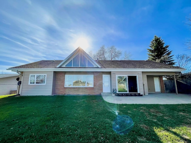 view of front of property featuring brick siding, a front lawn, fence, and a patio