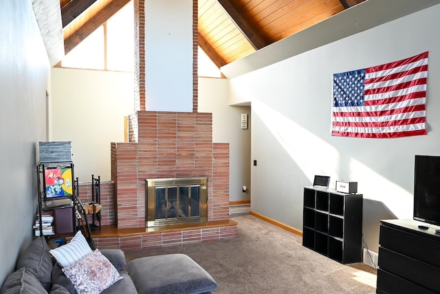 carpeted living area with wooden ceiling, baseboards, beamed ceiling, high vaulted ceiling, and a glass covered fireplace