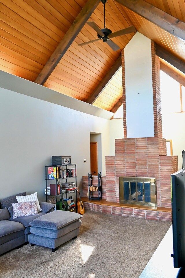 carpeted living room with beam ceiling, ceiling fan, high vaulted ceiling, wooden ceiling, and a tiled fireplace