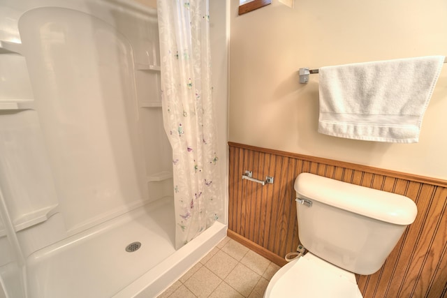 full bathroom with wainscoting, a stall shower, and toilet