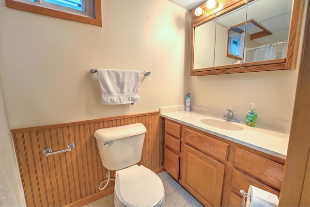 full bathroom featuring a wainscoted wall, tile patterned flooring, vanity, and toilet