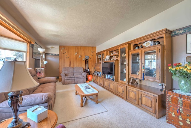 living area with carpet flooring, a textured ceiling, and wooden walls