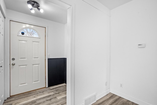 foyer with light wood-style floors, visible vents, and baseboards