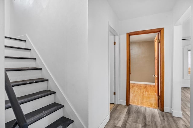 staircase featuring baseboards and wood finished floors