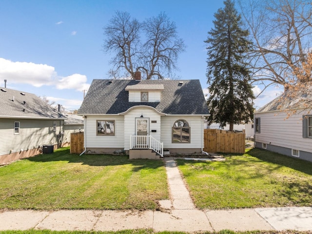 view of front of house featuring a chimney, roof with shingles, fence, and a front yard