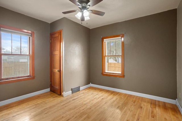 spare room featuring baseboards, a healthy amount of sunlight, and light wood-style floors