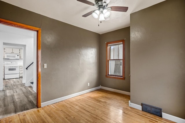 unfurnished room featuring visible vents, stairway, ceiling fan, wood-type flooring, and baseboards