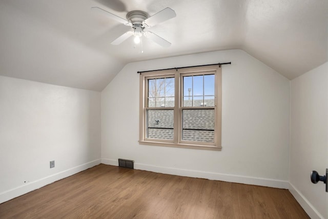 additional living space featuring wood finished floors, a ceiling fan, visible vents, baseboards, and vaulted ceiling