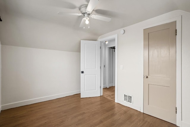 unfurnished bedroom featuring wood finished floors, visible vents, baseboards, ceiling fan, and lofted ceiling