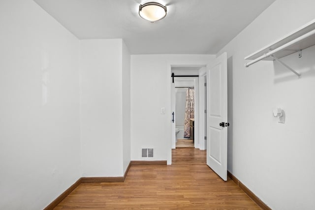 unfurnished room featuring baseboards, light wood-style flooring, and visible vents