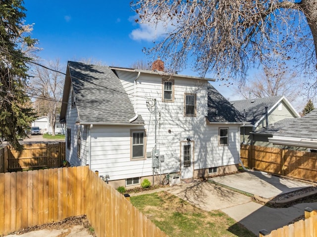 rear view of property with a fenced backyard, a patio, a shingled roof, and a chimney