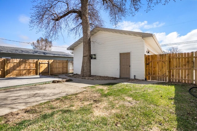 rear view of property featuring a gate, fence, and a lawn