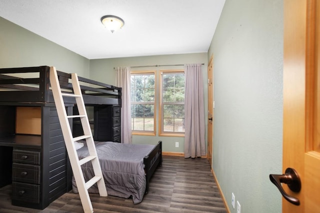 bedroom with baseboards and dark wood-type flooring