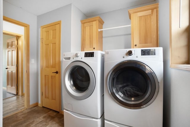 clothes washing area with separate washer and dryer, cabinet space, and baseboards