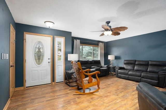 living area with baseboards, ceiling fan, and wood finished floors
