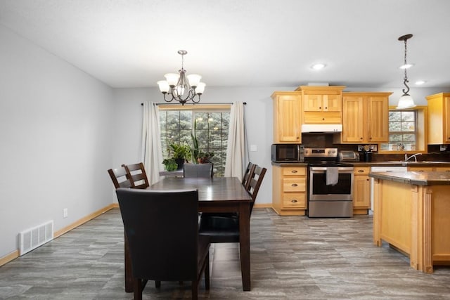 kitchen with under cabinet range hood, an inviting chandelier, visible vents, black microwave, and electric stove