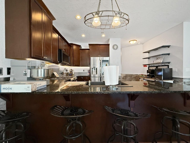 4005 Crossing St, Minot, ND 58701 - kitchen featuring dark stone countertops, a peninsula, appliances with stainless steel finishes, and a kitchen bar