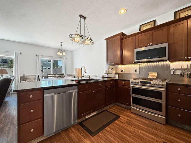 4005 Crossing St, Minot, ND 58701 - kitchen featuring a sink, a peninsula, a wealth of natural light, dark wood-style floors, and appliances with stainless steel finishes