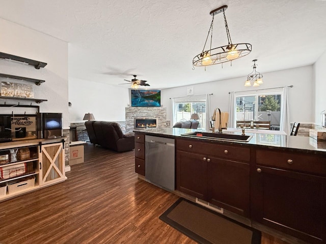 4005 Crossing St, Minot, ND 58701 - kitchen featuring a sink, dark countertops, stainless steel dishwasher, a stone fireplace, and ceiling fan