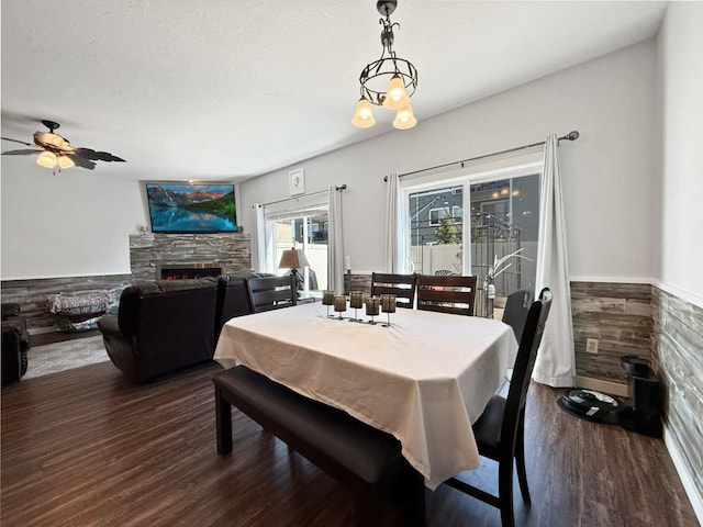 4005 Crossing St, Minot, ND 58701 - dining space with dark wood finished floors, a fireplace, ceiling fan, and a wainscoted wall