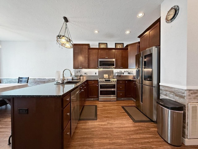 4005 Crossing St, Minot, ND 58701 - kitchen featuring a peninsula, a sink, stainless steel appliances, visible vents, and dark wood-style flooring