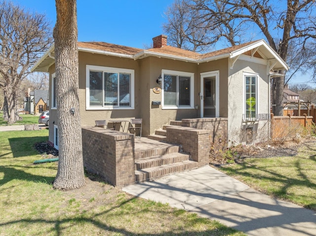 724 3rd Ave, Minot, ND 58703 - bungalow with stucco siding, a chimney, a front yard, and fence
