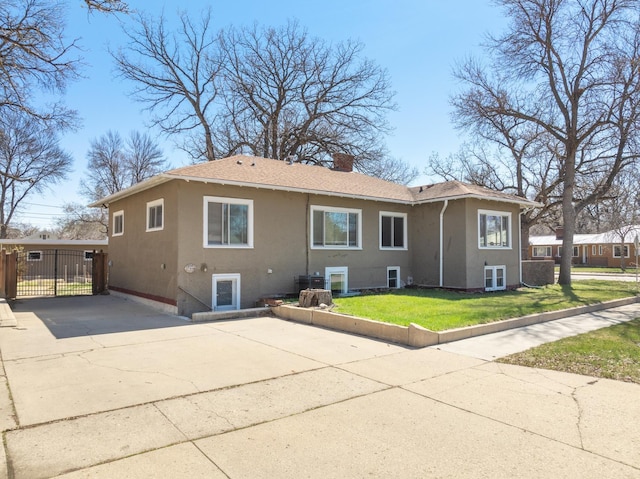724 3rd Ave, Minot, ND 58703 - back of house with a lawn, a chimney, stucco siding, and driveway