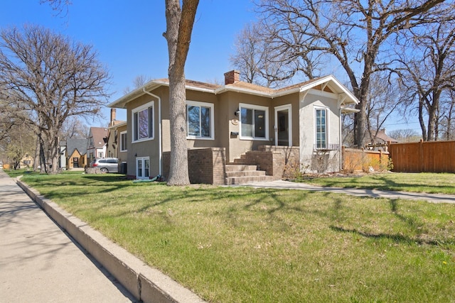 724 3rd Ave, Minot, ND 58703 - view of front of property with fence, brick siding, stucco siding, a front lawn, and a chimney