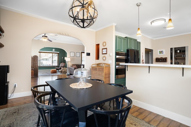 724 3rd Ave, Minot, ND 58703 - dining space featuring baseboards, dark wood-style flooring, ceiling fan with notable chandelier, crown molding, and arched walkways