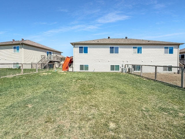back of property featuring stairway, a deck, a fenced backyard, and a yard