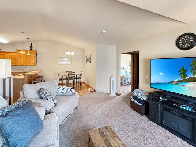 living area with vaulted ceiling, an inviting chandelier, carpet, and baseboards