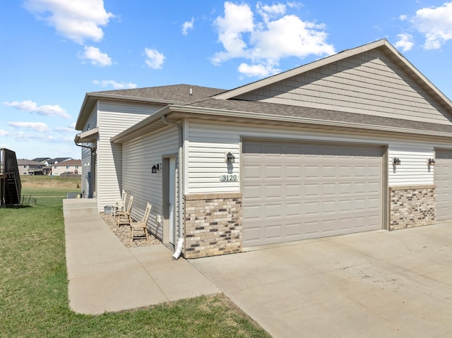 view of home's exterior with roof with shingles, concrete driveway, brick siding, and a lawn