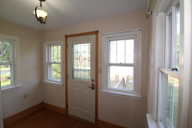 doorway featuring baseboards and dark wood-type flooring
