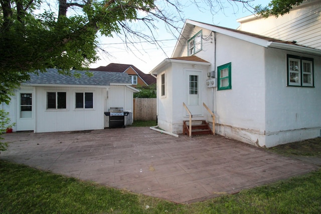 rear view of property featuring stucco siding, fence, a shingled roof, a patio area, and entry steps