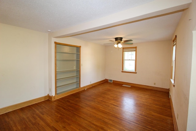 empty room with visible vents, wood finished floors, and built in shelves