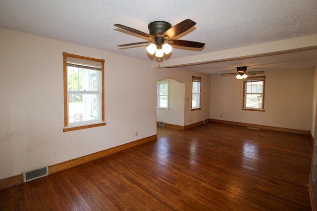 unfurnished room with a ceiling fan, a wealth of natural light, visible vents, and wood finished floors