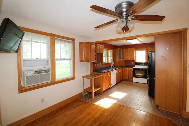 kitchen with brown cabinets, freestanding refrigerator, cooling unit, white dishwasher, and range with electric cooktop